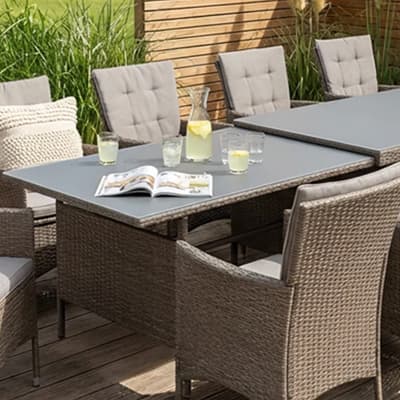 Graues Sofa mit gemusterten Kissen vor blauer Wand mit Kunstbildern, daneben schwarzes Regal und gemusterter Beistelltisch