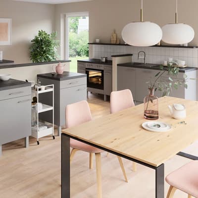 Moderne Küche mit grauen Schränken, Holz-Esstisch, rosa Stühlen und weißen Lampen. Pflanzen und Geschirr auf den Arbeitsflächen.