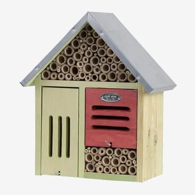Grünes und rotes Insektenhotel aus Holz mit vielen Röhren und Schlitzen unter einem silbernen Dach.