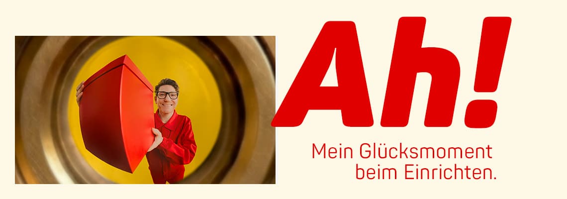 Ah! Mein Glücksmoment beim Einrichten – Person in roter Kleidung hält roten Würfel vor gelbem Hintergrund